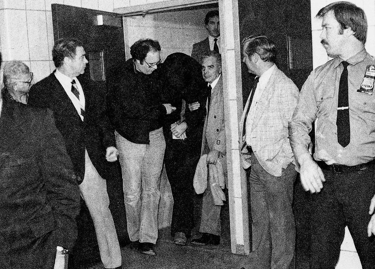 FILE – In this Dec. 9. 1980, file photo, police lead suspect Mark David Chapman, with his head covered, from the 20th Precinct on New York’s Upper West Side. Thirty-five years ago, Mark David Chapman shot and killed John Lennon, a former Beatles member. (AP Photo/David Handshuh, File)