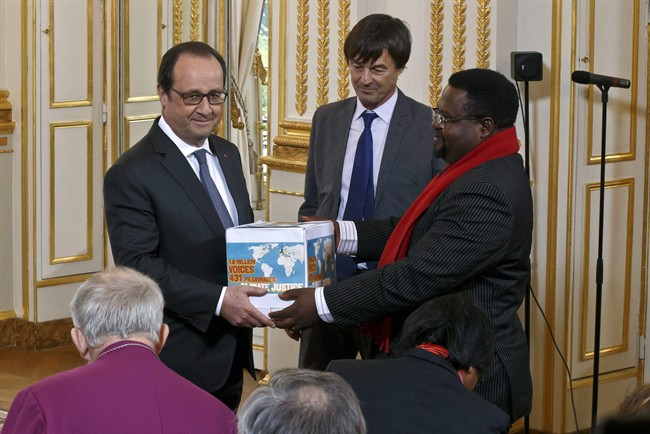 Cameroon's Augustine Njamnshi of the Pan African Climate Justice Alliance, right, hands over to France's President Francois Hollande, left, a box containing an international petition to support the climate talks while French environmentalist Nicolas Hulot stands between at the Elysee Palace in Paris, Thursday, Dec. 10, 2015. France's President Francois Hollande met religious figures lobbying against climate change on the side line of the COP21, United Nations Climate Change Conference in Le Bourget.