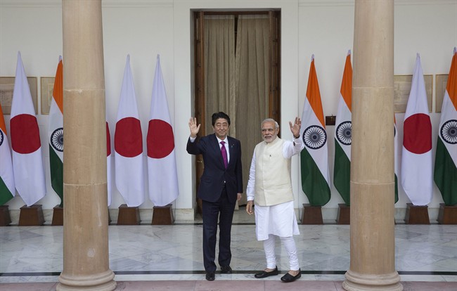 Indian Prime Minister Narendra Modi, right, with his Japanese counterpart Shinzo Abe wave to the media before their meeting, in New Delhi, India , Saturday, Dec. 12, 2015.