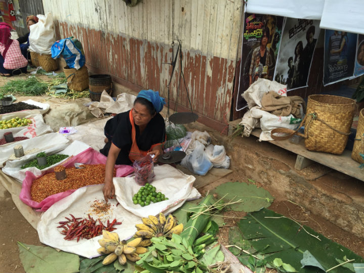 A woman sells vegetables in a market in the Inle Lake region of Myanmar. She is wearing a headscarf in the traditional patterns and colors of Shan State.