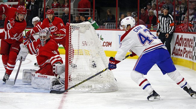 Montreal Canadiens' Daniel Carr (43) wraps the puck around the net to slip it past Carolina Hurricanes goalie Cam Ward (30) with Hurricanes Noah Hanifin (5) nearby during the first period of an NHL hockey game, Saturday, Dec. 5, 2015, in Raleigh, N.C.