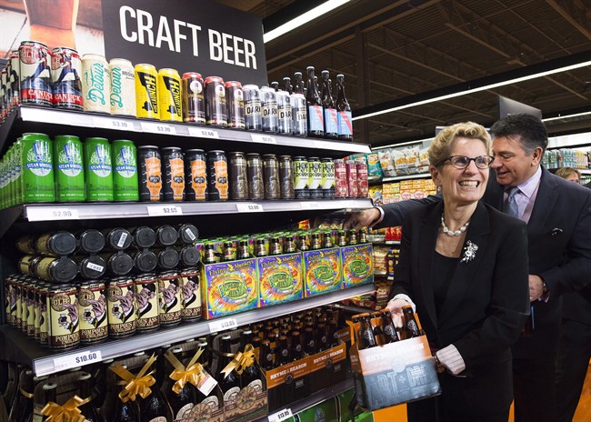 Ontario Premier Kathleen Wynne, left, and Minister of Finance Charles Sousa, right, pick beer at a Loblaws grocery store in Toronto on Tuesday, December 15, 2015. 