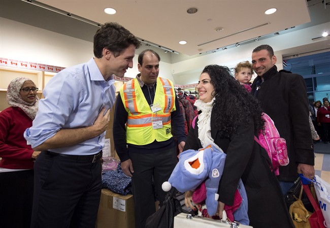 Canadian Prime Minister Justin Trudeau greets a family of refugees from Syria as they arrive at Pearson International airport, in Toronto, on Friday, Dec. 11, 2015. Sunday marks the one year anniversary of their arrival.