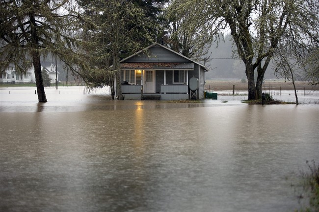 A home is flooded along Oregon 47 from the Nehalem River, Wednesday, Drec. 9, 2015, in Portland, Or. Torrential rains pummeled parts of the Pacific Northwest for another night, causing mudslides and flooding roads, leaving an Oregon woman dead after a tree fell onto her house and sweeping seven people into a Washington river, where they were rescued. 