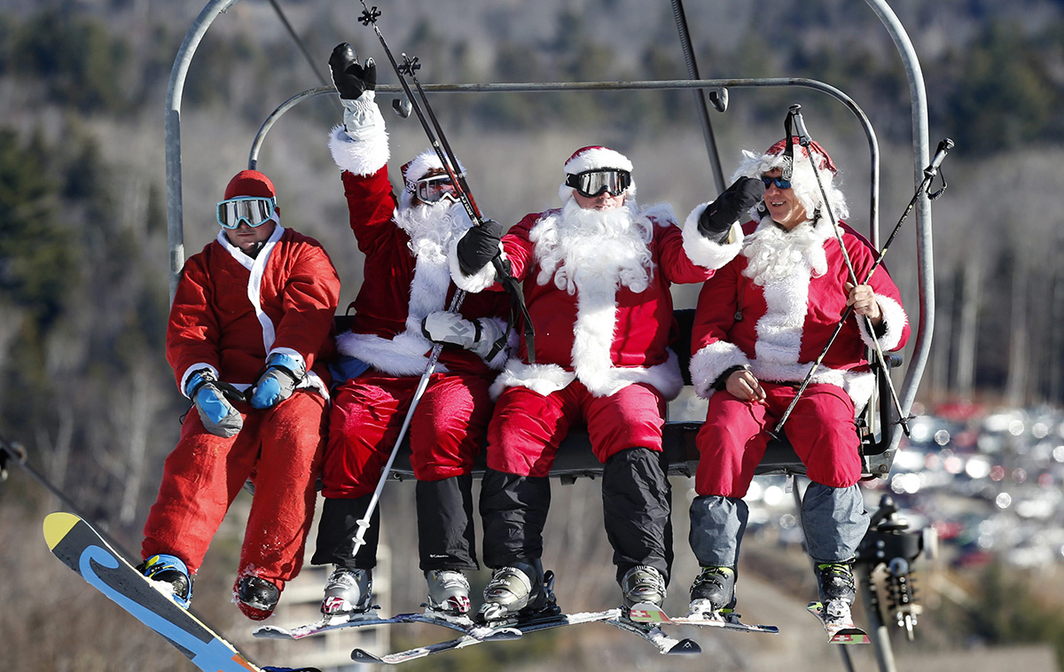 A snowboarder and skiers dressed as Santa bring the holiday spirit to the Sunday River ski resort, Sunday, Dec. 6, 2015, in Newry, Maine. The annual Santa Sunday fundraising event raised $3,014 for the Sunday River Community Fund.
