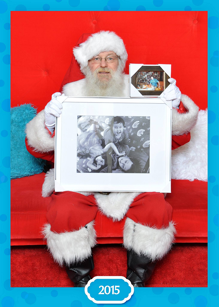 Santa Claus poses with a photograph of the Neville-Lake children and their grandfather.