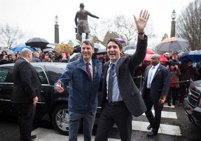 Prime Minister Justin Trudeau, right, waves as he's welcomed by Mayor Gregor Robertson, left, during a visit to City Hall in Vancouver, B.C., on Thursday December 17, 2015. 