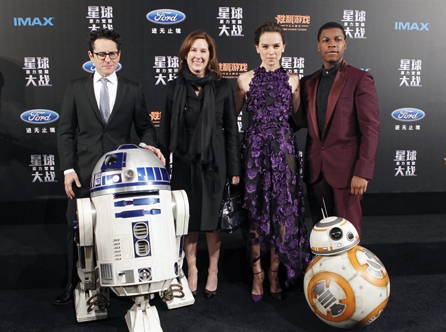 From left, director J.J. Abrams, producer Kathleen Kennedy, actress Daisy Ridley and actor John Boyega pose with droids character BB-8 and R2-D2 on stage during the premiere of "Star Wars: The Force Awakens" in Shanghai, China, Sunday, Dec. 27, 2015.