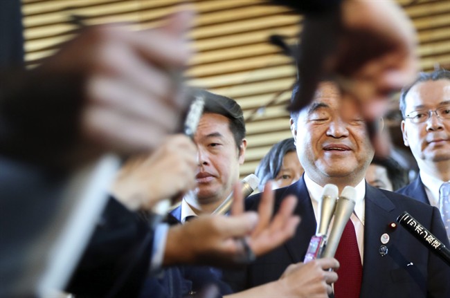 Toshiaki Endo, second right, minister in charge of the 2020 Tokyo Olympics, speaks with media after a meeting of Cabinet ministers including Japan's Prime Minister Shinzo Abe, on a new national stadium construction plan for the 2020 Tokyo Olympics at Abe's official residence in Tokyo Tuesday, Dec. 22, 2015.