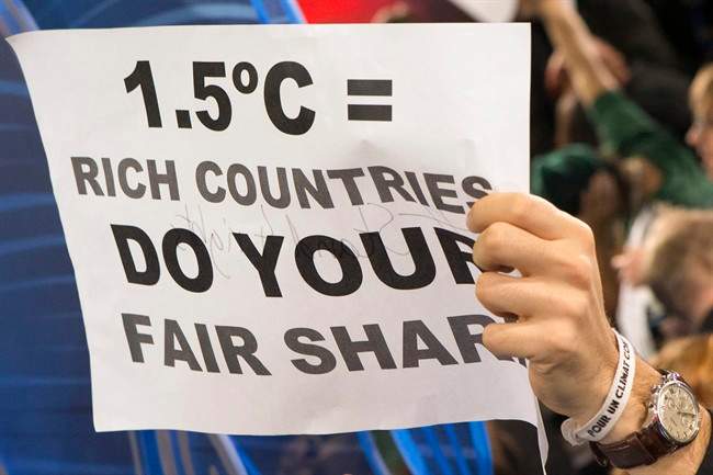 A participant holds a poster amid NGO representatives staging a sit-in protest closed to the plenary session to denounce the first draft COP21 Climate Conference agreement, and put pressure to reach an international agreement to limit global warming, during the COP21, United Nations Climate Change Conference in Le Bourget, north of Paris, France, Wednesday, Dec. 9, 2015. 