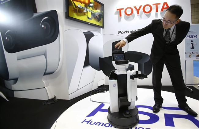 Toyota Motor Cop,. Partner Robot Div. General Manager Akifumi Tamaki speaks with Toyota partner robot HSR during an interview at the International Robot exhibition in Tokyo, Wednesday, Dec. 2, 2015. 