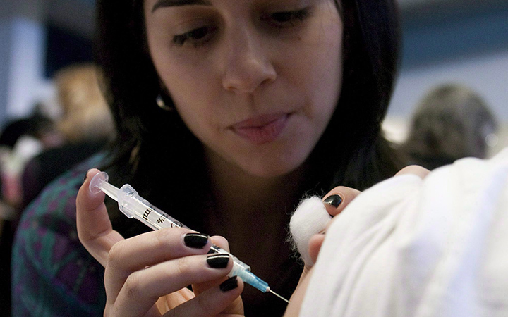 Nurse Laura Gill injects the a flu vaccine into a young male in Ottawa on November 2, 2009. 