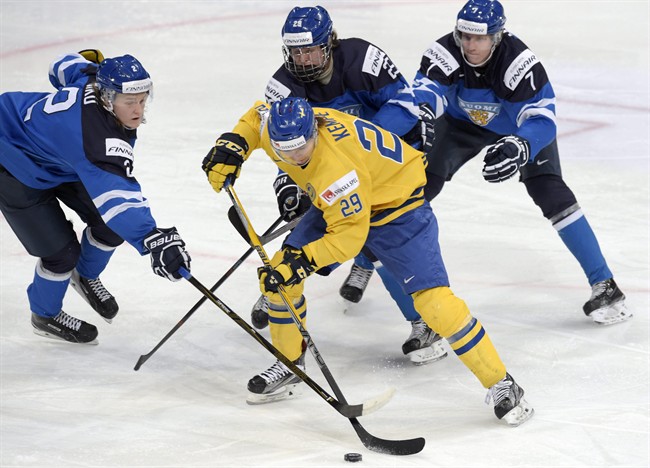 Sweden's Adrian Kempe, centre, is surrounded by Finland's Sami Niku, left, Patrik Laine and Niko Mikkola, right, during the 2016 IIHF World Junior Ice Hockey Championship semifinal match between Sweden and Finland in Helsinki, Monday, Jan. 4, 2016. 