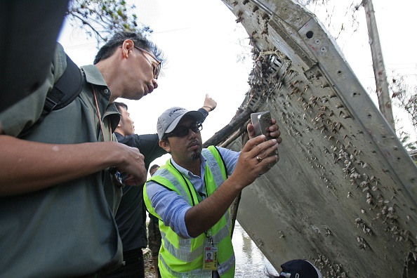 A Malaysian official (C) takes pictures of a piece of suspected aircraft debris after it was found by fishermen on January 23, at a beach in the southern province of Nakhon Si Thammarat on January 25, 2016.  Thailand's air force said it would bring a piece of suspected aircraft debris - a metal panel measuring two metres (6.6 feet) by three metres - found on the southeast coast to Bangkok, amid media speculation it may belong to missing Malaysia Airlines Flight MH370. 