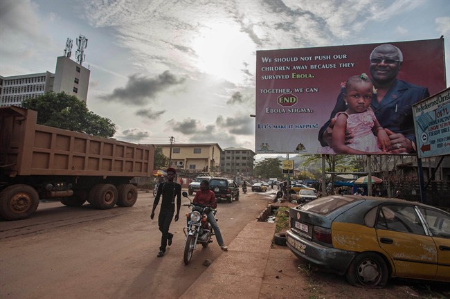 A man walk past a poster reading 'We should not push our children away because they survived Ebola' forming part of Sierra Leone's Ebola campaign in the city of Freetown, Sierra Leone, Friday, Jan. 15, 2016.