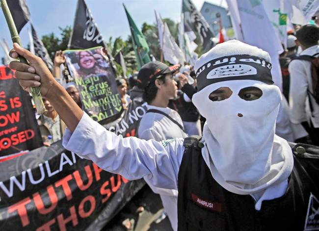 In this June 18, 2014, file photo, a man wears a headband showing the Islamic State group's symbol during a protest calling for the closure of a local prostitution complex in Surabaya, Indonesia. Experts say it is difficult to know how much of a foothold the Islamic State group has established in Indonesia. But the bombing attack at a Starbucks cafe on Thursday, Jan. 14, 2016, achieved two things: Showing that domestic militants, who’ve been besieged and fragmented by a concerted counter-terrorism campaign, are still capable of attacks, and suggesting that the Islamic State group has expanded its ability to launch attacks in Southeast Asia for the first time. (AP Photo/Dita Alangkara, File)