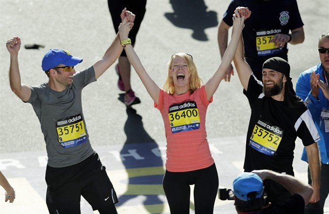Timothy Haslet, left, and David Haslet, right, celebrate with their sister Adrianne Haslet-Davis at the finish line of the 118th Boston Marathon, after she completed a short distance of the course in Boston, April 21, 2014.