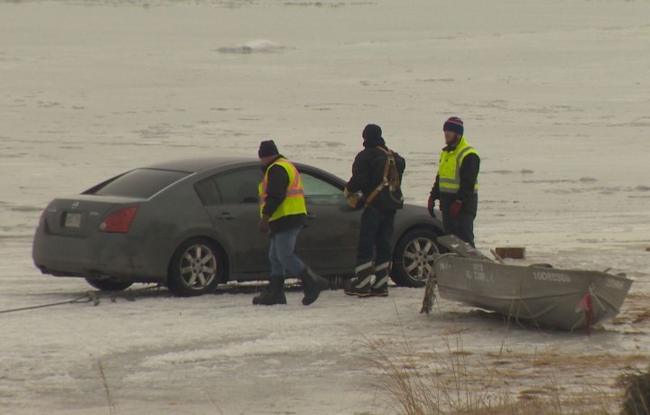 Workers remove a car that had fallen through the ice on the Saint Lawrence River, Thursday, January 28, 2016.