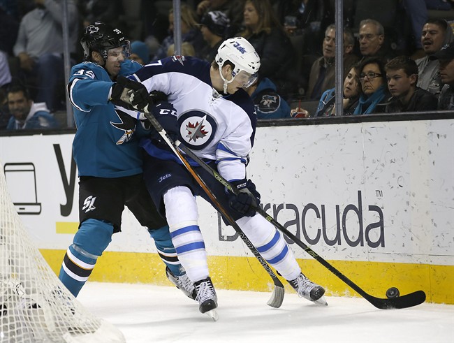San Jose Sharks’ Logan Couture vies for the puck against Winnipeg Jets’ Adam Lowry during the second period of a game in San Jose, California on January 2, 2016. Lowry will return to the Jets lineup tonight after missing the last five games with an injury.