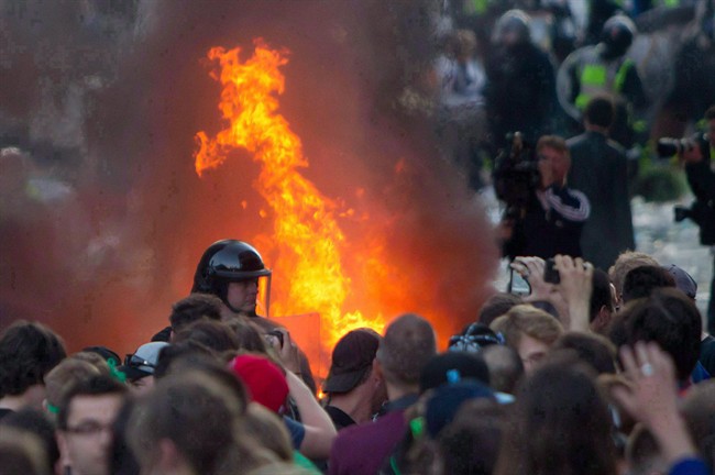 A car burns behind a police officer after a riot broke out after the Vancouver Canucks were defeated by the Boston Bruins in the NHL Stanley Cup Final in Vancouver, B.C., on Wednesday June 15, 2011. It cost almost $5 million to process hundreds of people through the justice system after the Stanley Cup riot in Vancouver five years ago.