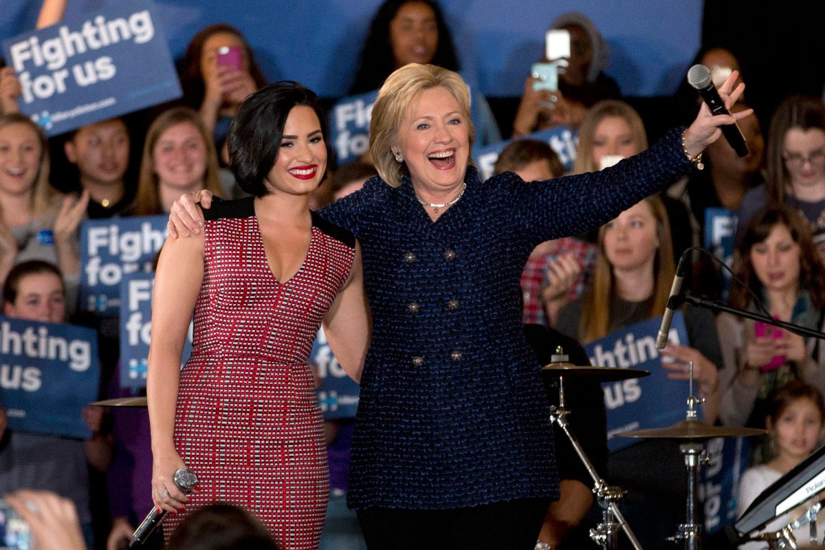 In this photo taken Jan. 21, 2016, Democratic presidential candidate Hillary Clinton and musician Demi Lovato acknowledge the cheering crowd at a rally on the campus of University of Iowa in Iowa City, Iowa.
