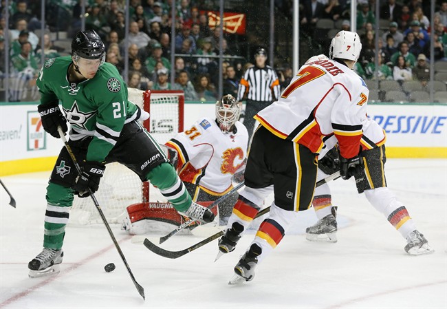 Dallas Stars left wing Antoine Roussel (21) of France and Calgary Flames' T.J. Brodie (7) compete for control of the puck in the first period of an NHL hockey game, Monday, Jan. 25, 2016, in Dallas. 