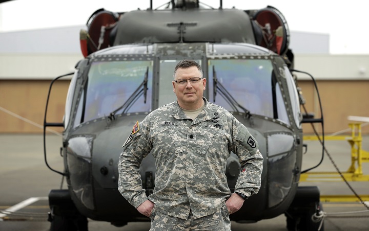 Lt. Col. Clayton Braun, of the Washington State Army National Guard, poses for a photo, Wednesday, Jan. 20, 2016, at Joint Base Lewis-McChord in Washington state in front of a military helicopter that could be used in response to a major earthquake. 