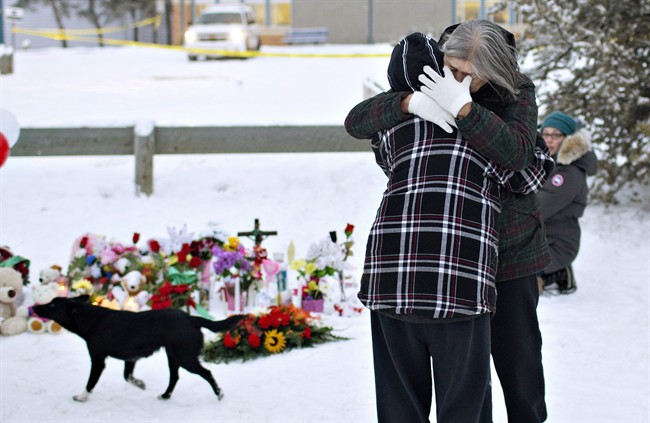 Residents console each other at the memorial near the La Loche Community School in La Loche, Sask., on Sunday. January 24, 2016. John McCoy, a U.S. politician whose community was ripped apart by a 2014 school shooting, offers advice in the wake of the La Loche shooting Friday left four people dead.