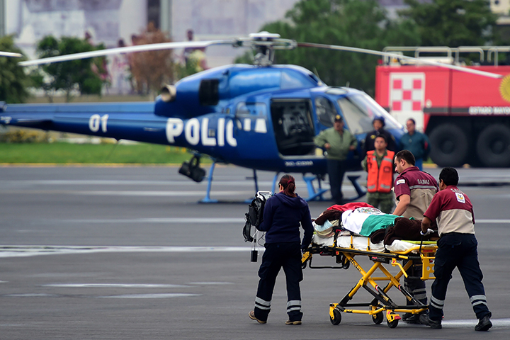 A Mexican tourist wounded in a military attack in Egypt is taken to hospital on a strecher by rescuers wrapped in the Mexican flag at the presidential hangar at Mexico City's airport upon deplaning from the presidential aircraft on September 18, 2015. 