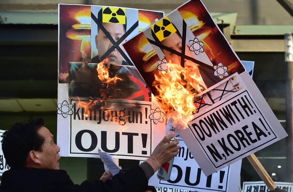 South Korean activists burn placards showing portraits of North Korean leader Kim Jong-Un during a rally denouncing North Korea's hydrogen bomb test, in Seoul on January 7, 2016.