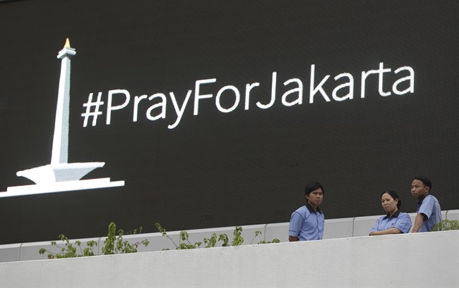 Workers stand near an electronic screen showing a message supporting the city atop the Starbucks cafe where Thursday's attack occurred in Jakarta, Indonesia, Friday, Jan. 15, 2016.