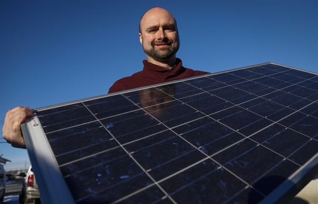 Curtis Buxton, a project manager at Skyfire Energy Inc., who was forced to look for new employment after being downsized out of the oil and gas industry, poses with solar panels, in Calgary on Monday, Jan. 25, 2016.