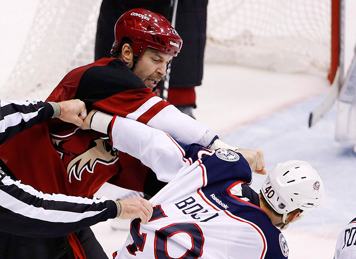 Arizona Coyotes' John Scott, left, punches Columbus Blue Jackets' Jared Boll during a fight in the second period of an NHL hockey game Thursday, Dec. 17, 2015, in Glendale, Ariz. 