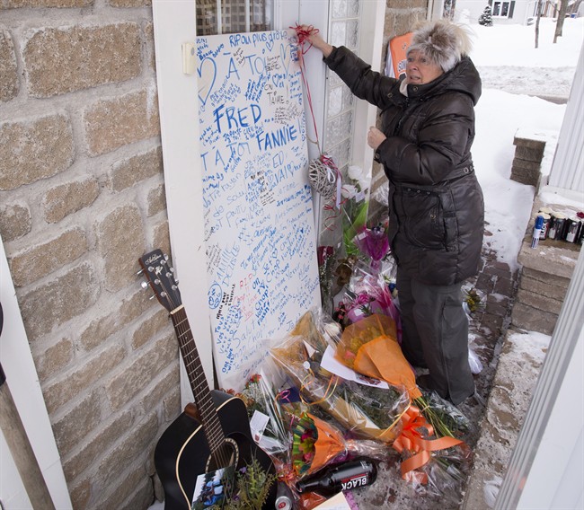 A woman puts a note on a makeshift memorial in honour of Yves Carrier, his son Charlelie Carrier, daughter Maude Carrier and wife Gladys Chamberland who died in a terrorist attack in Burkina Faso, Monday, January 18, 2016 at the Carrier home in Lac-Beauport, Que.