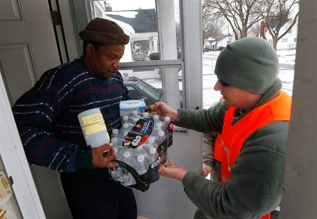 Louis Singleton receives water filters, bottled water and a test kit from Michigan National Guard Specialist Joe Weaver as clean water supplies are distributed to residents, Jan. 21, 2016 in Flint, Mich. 