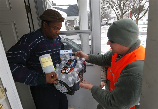 Louis Singleton receives water filters, bottled water and a test kit from Michigan National Guard Specialist Joe Weaver as clean water supplies are distributed to residents, Jan. 21, 2016 in Flint, Mich. 