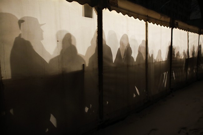 Migrants are silhouetted as they warm themselves inside a waiting tent to get an appointment at the central registration center for refugees and asylum seekers LaGeSo (Landesamt fuer Gesundheit und Soziales - State Office for Health and Social Affairs) in Berlin, Wednesday, Jan. 6, 2016. (AP Photo/Markus Schreiber).