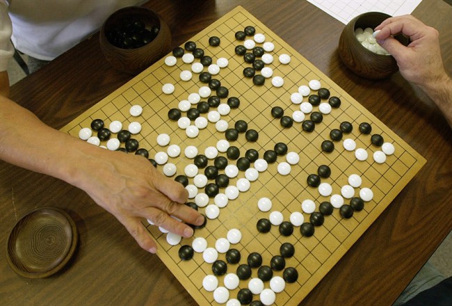 FILE - A player places a black stone while his opponent waits to place a white one as they play Go, a game of strategy, in the Seattle Go Center, Tuesday, April 30, 2002. The game, which originated in China more than 2,500 years ago, involves two players who take turns putting markers on a grid. The object is to surround more area on the board with the markers than one's opponent, as well as capturing the opponent's pieces by surrounding them. A paper released Wednesday, Jan. 27, 2016 describes how a computer program has beaten a human master at the complex board game, marking significant advance for development of artificial intelligence.