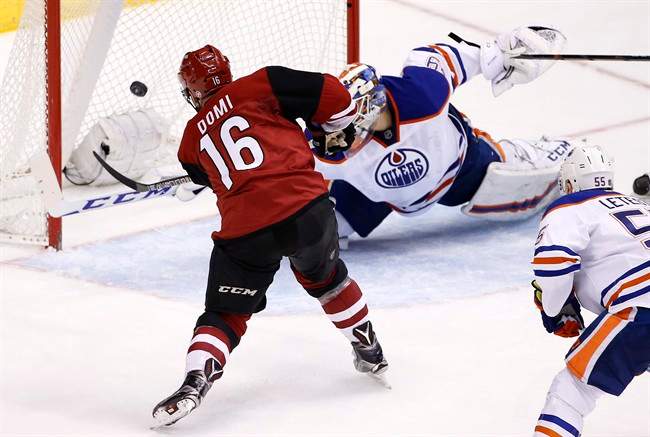 Arizona Coyotes' Max Domi (16) scores a goal on Edmonton Oilers' Anders Nilsson, top right, of Sweden, as Oilers' Mark Letestu (55) watches during the second period of an NHL hockey game Tuesday, Jan. 12, 2016, in Glendale, Ariz. 