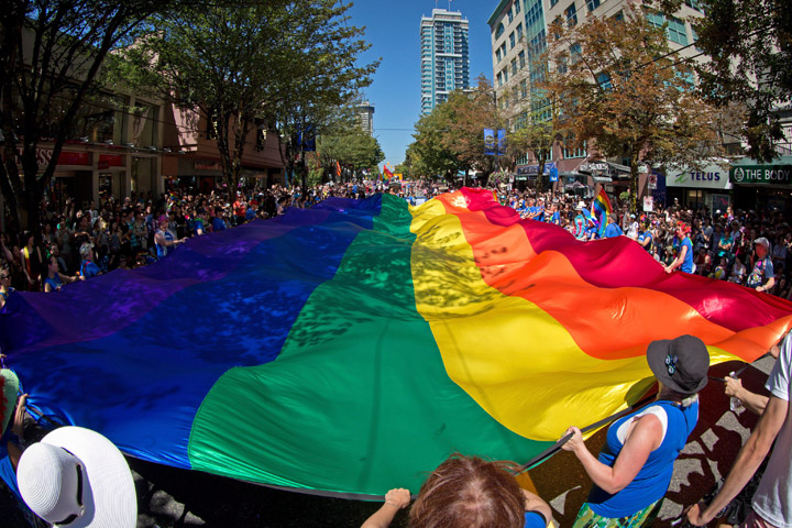 People carry an oversized rainbow flag down Robson Street during the Vancouver Pride Parade in Vancouver, B.C., on Sunday, August 3, 2014. 