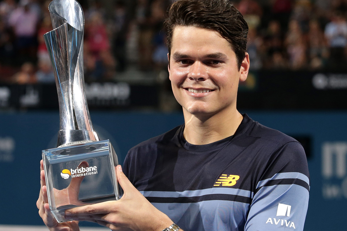 Milos Raonic of Canada smiles with the winner's trophy after winning his men's final match against Roger Federer of Switzerland 6-4, 6-4 during the Brisbane International tennis tournament. 