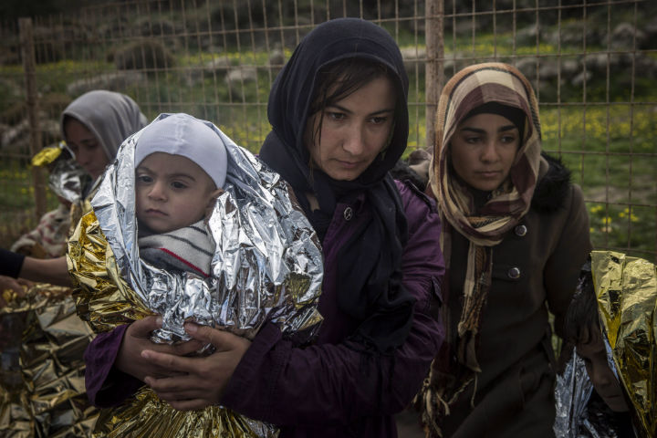 Women and children stand on a road after their arrival on a dinghy with other refugees and migrants from the Turkish coast to the Greek island of Lesbos, on Wednesday, Nov. 25, 2015.  (File photo).