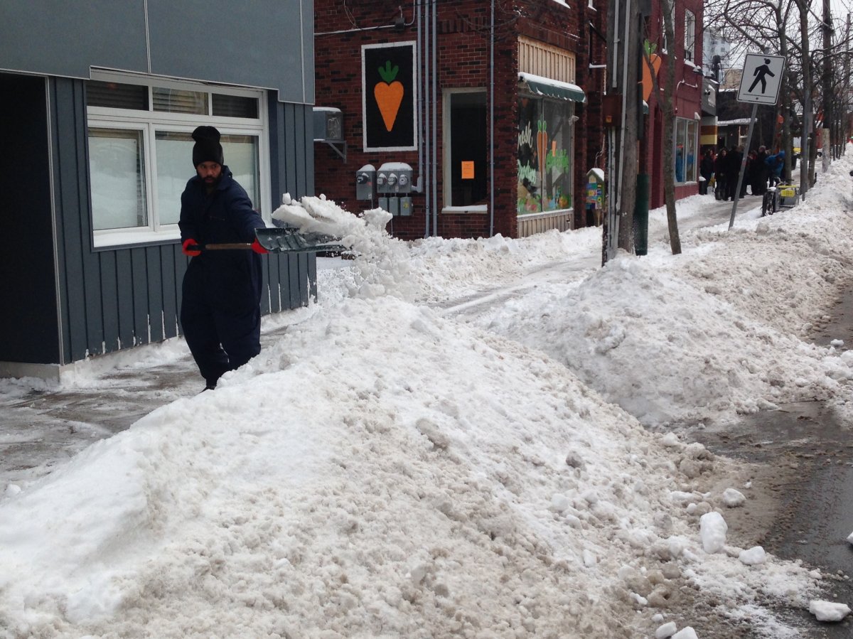A man clears the sidewalk on Gottingen Street, in Halifax on Jan. 17, 2016. City crews say they're on target to clear the roads before the Monday commute.