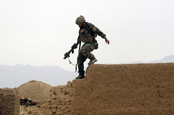 In this Sunday, Nov. 1, 2009 file photo, a member of U.S. special operations forces climbs down from a compound wall during a joint patrol with Afghan National Army soldiers in Shewan, Afghanistan. 