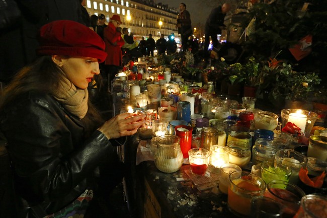 Mastioucha Peres, 30, from Paris, lights candles during a gathering that marks one year after the attacks on Charlie Hebdo satirical newspaper, in Paris, France, Thursday, Jan. 7, 2016. It's a year to the day since an attack on the French satirical newspaper Charlie Hebdo launched a bloody year in the French capital. Tensions in France, under a state of emergency since a wave of attacks on Nov. 13, have been even higher this week as the anniversary of the January attacks approached. (AP Photo/Francois Mori).