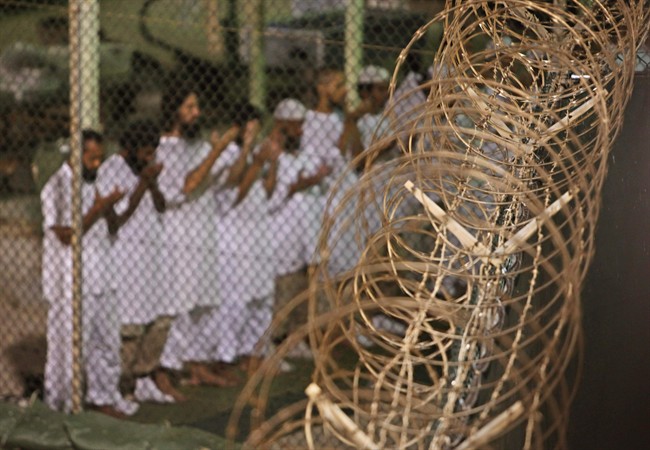 In this May 14, 2009 file photo, reviewed by the U.S. military, Guantanamo detainees pray before dawn near a fence of razor-wire, inside Camp 4 detention facility at Guantanamo Bay U.S. Naval Base, Cuba. 