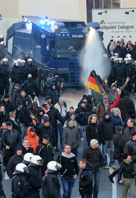 Police drive back right-wing demonstrators using a water cannon during protests in Cologne, Germany, Saturday Jan. 9, 2016. Women’s rights activists, far-right demonstrators and left-wing counter-protesters all took to the streets of Cologne on Saturday in the aftermath of a string of New Year’s Eve sexual assaults and robberies in Cologne blamed largely on foreigners. ( Roland Weihrauch/dpa via AP).