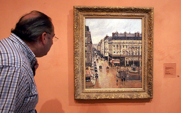 An unidentified visitor looks at the Impressionist painting called "Rue St.-Honore, Apres-Midi, Effet de Pluie" painted in 1897 by Camille Pissarro, on display in the Thyssen-Bornemisza Museum in Madrid.  