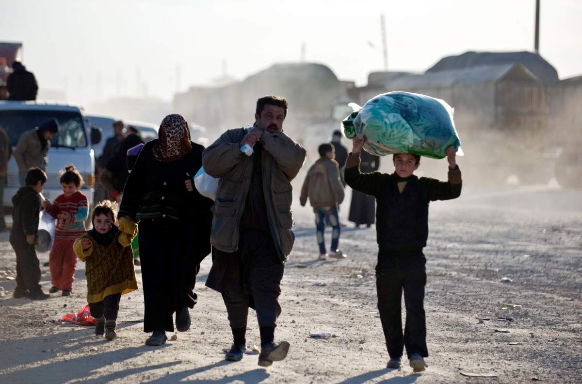 Syrians walk towards the Turkish border at the Bab al-Salam border gate, Syria, Friday, Feb. 5, 2016. 