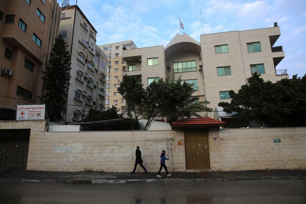 Palestinian walk past an office of the International Committee of the Red Cross that was temporarily closed after protesters repeatedly tried to storm it, in Gaza City, Sunday, Feb. 7, 2016. Dozens of Gazans have protested daily at the office in recent weeks in solidarity with a Palestinian hunger striker detained by Israel, demanding that the Red Cross do more to bring about his release.